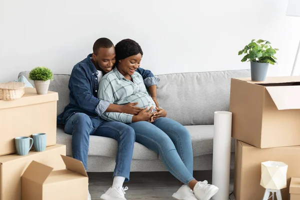 Vivienda Familiar. Feliz pareja afroamericana embarazada sentada en un sofá en un apartamento nuevo — Foto de Stock