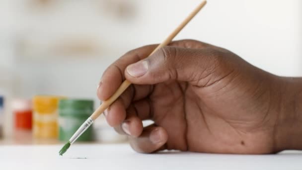 Неузнаваемый афроамериканец рисует акварелью в помещении, крупным планом — стоковое видео