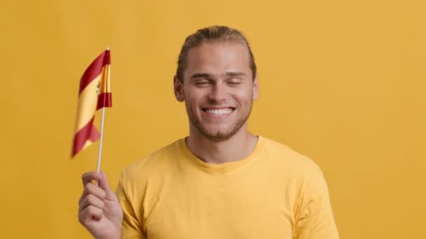 Bonito jovem patriótico acenando com a bandeira da Espanha, sorrindo para a câmera — Vídeo de Stock