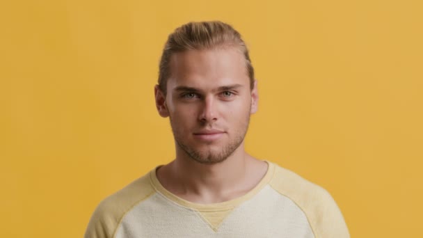Primer plano retrato de guapo joven rubia posando sobre amarillo estudio fondo — Vídeo de stock