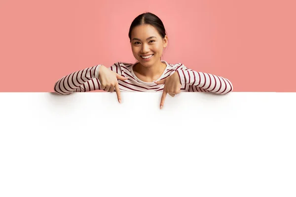 Cheerful Young Asian Woman Leaning And Pointing At Blank White Advertisement Board — Stock Photo, Image