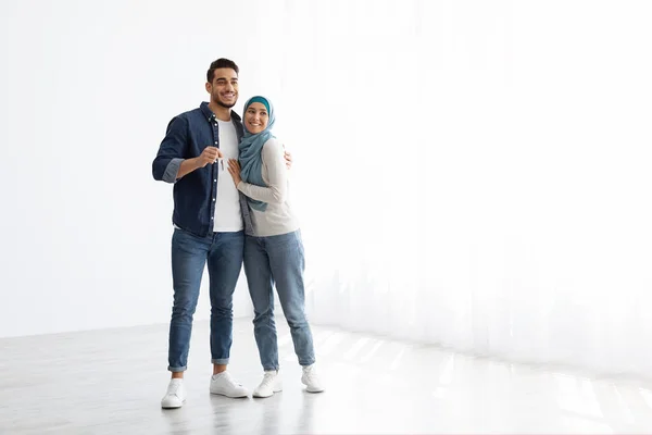 Feliz pareja musulmana posando en un apartamento vacío, mostrando la llave — Foto de Stock