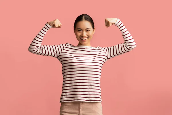 Feminisme concept. Sterke krachtige aziatische dame heffen handen en tonen haar biceps — Stockfoto