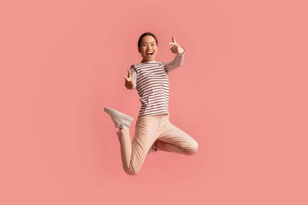 Glada asiatiska kvinnor hoppar upp i luften och pekar på kameran — Stockfoto