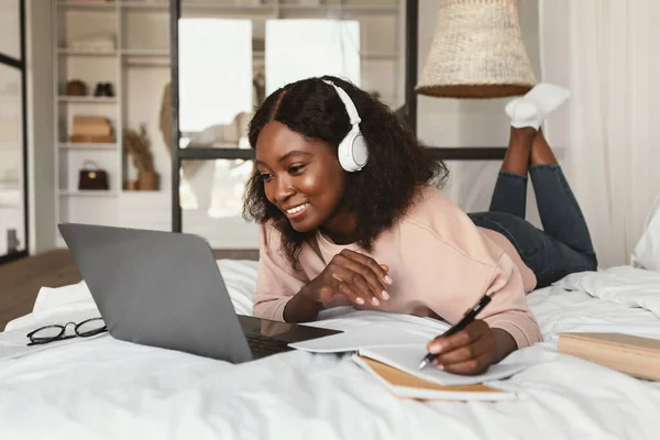 Afrikanerin macht sich mit Laptop Notizen im Schlafzimmer — Stockfoto