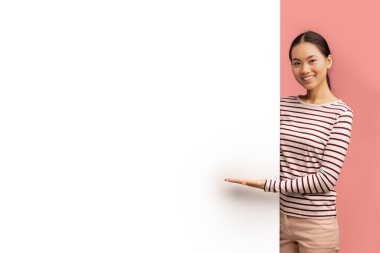 Güzel, gülümseyen Asyalı bayan, içi boş reklam panosunu işaret ediyor.