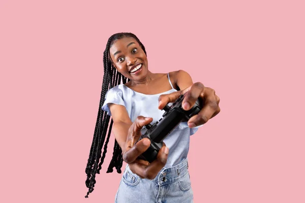 Conceito de entretenimento moderno. Jovem mulher negra excitada com joystick jogando videogame no fundo do estúdio rosa — Fotografia de Stock