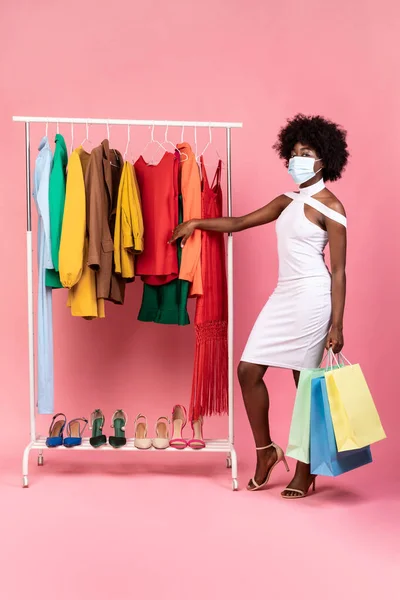 Africano Feminino Vestindo Máscara Compras Escolher Roupas Sobre Fundo Rosa — Fotografia de Stock