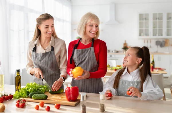 Щаслива сім'я багато поколінь готує разом, ріже овочі для святкового обіду на кухні — стокове фото