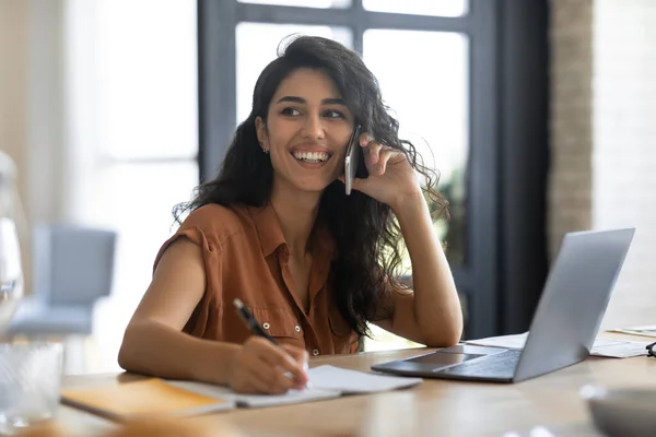 Glada unga affärskvinna pratar på mobilen, använder laptop, arbetar hemifrån. Modern teknik — Stockfoto