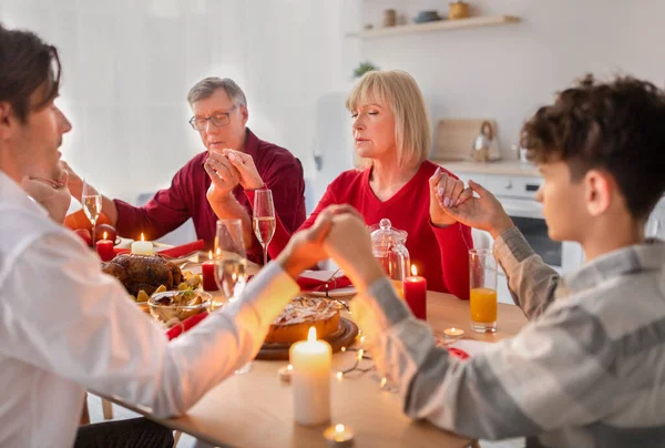 Vallásos, tágabb család fogja egymás kezét és imádkoznak ünnepi karácsonyi vagy hálaadási vacsora előtt pulykával otthon — Stock Fotó