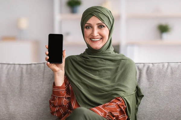 Érett muszlim hölgy Mutató mobiltelefon üres képernyő otthon — Stock Fotó