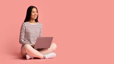 Uzaktan kumanda. Sırıtkan Asyalı genç bir kadının kucağında dizüstü bilgisayarla oturup fotokopi stüdyosundaki yerine bakarken mutlu Koreli bir kadının portresi.