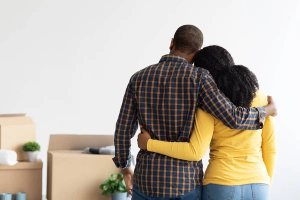 Svart par som står i rummet med kartonger efter flytt, bakåtsikt — Stockfoto