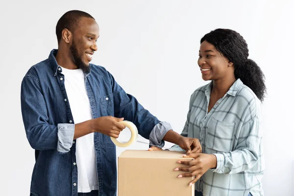 Vreugdevolle zwarte echtgenoten verhuizen naar een nieuw huis, Verpakking van bezittingen in kartonnen dozen — Stockfoto