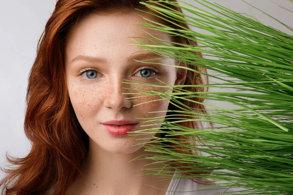 Senhora Millennial de cabelo de gengibre olhando através de grama verde, Studio Shot — Fotografia de Stock