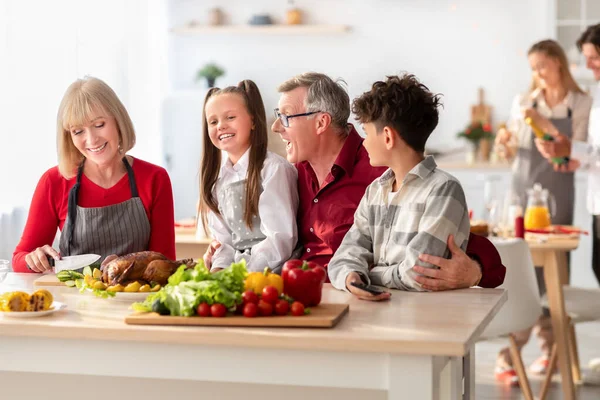 Щаслива сім'я з бабусею і дідусем і онуками, які готують святкове подяку або різдвяну страву на кухні — стокове фото