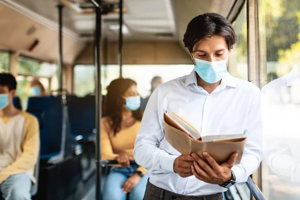 Összpontosított ember maszk olvasás könyv megy autobus — Stock Fotó