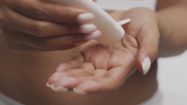 Conceito de cuidados com o corpo. Mulher afro-americana irreconhecível espremendo creme hidratante na palma da mão do tubo — Vídeo de Stock