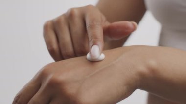 Kadın vücut bakımı. Tanımlanamayan Afrikalı Amerikalı kadın avuç içine şımartıcı el kremi sürüyor.