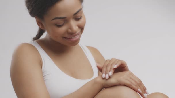 Joven mujer afroamericana bastante positiva aplicando crema de manos en la piel, disfrutando de los procedimientos de cuidado de la belleza personal — Vídeo de stock