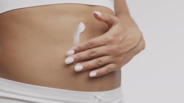 Schlankheits- und Hautpflege. Junge schwarze, unkenntliche Frau trägt Anti-Cellulite-Creme auf ihren Bauch auf — Stockvideo