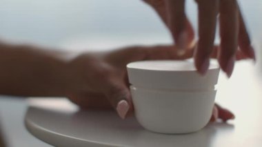 Favori kadın kozmetik ürünleri. Tanımlanamayan bir kadın, günlük güzellik prosedürleri için beyaz bir kavanoz açıyor.