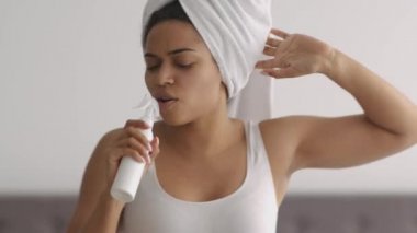 Enerjik bir sabah dilerim. Genç, Afro-Amerikan kadın duştan sonra eğleniyor, evde kozmetikle şarkı söylüyor.,