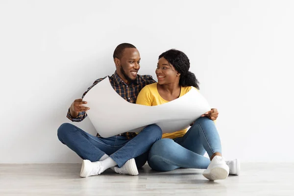 Heureux couple noir assis avec des plans directeurs planification design d'intérieur dans un nouvel appartement — Photo
