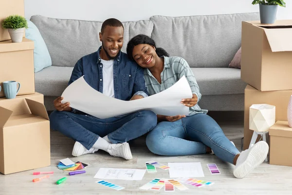 Cônjuges negros felizes planejando o projeto de sua nova casa juntos — Fotografia de Stock