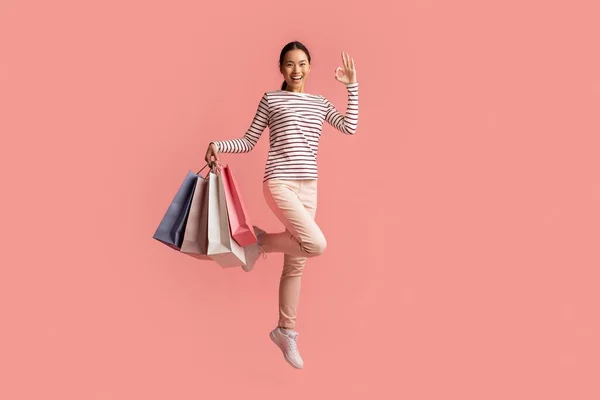 Big Sales Concept. Happy Asian Female Jumping With Shopping Bags And Showing Ok Gesture, Excited Young Korean Woman Enjoying Seasonal Discounts, Posing Isolated Over Pink Background, Copy Space — Stock Photo, Image