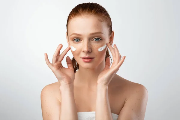 Junge Frau trägt Gesichtscreme mit beiden Händen auf, Studioaufnahme — Stockfoto