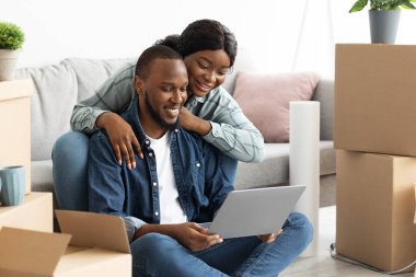 Gülümseyen Siyah Eşler Dizüstü bilgisayarlarıyla Yeni Daireleri için Dekorasyon Düzenliyor