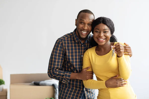 Счастливые хозяева. Веселые чернокожие супруги позируют с ключами от своего нового дома — стоковое фото