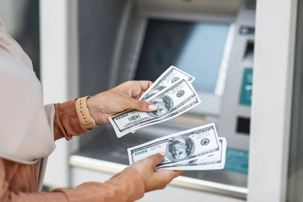 Irreconhecível milenar árabe senhora conta um monte de dólares perto ATM ao ar livre — Fotografia de Stock