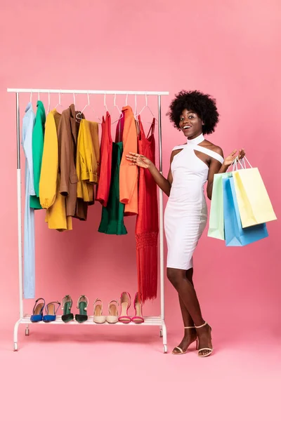 Africano americano mulher compras e posando segurando sacos, fundo rosa — Fotografia de Stock