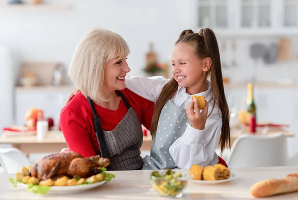Семейная кухня. Счастливая бабушка обнимает симпатичную девушку, делает традиционный День благодарения или рождественский ужин на кухне — стоковое фото