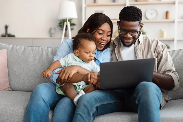 Gelukkig zwart gezin met laptop in de woonkamer — Stockfoto