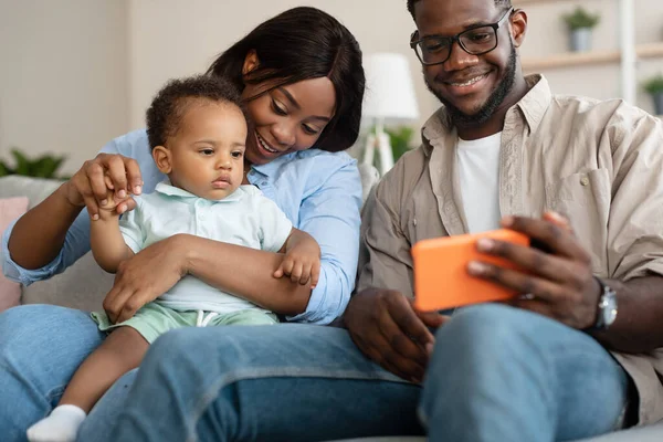 Портрет африканской американской семьи, использующей мобильный телефон дома — стоковое фото