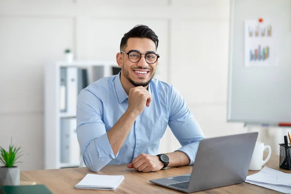 Портрет счастливого арабского бизнесмена, использующего ноутбук, делающего видеозвонок, общающегося онлайн с коллегой в офисе — стоковое фото