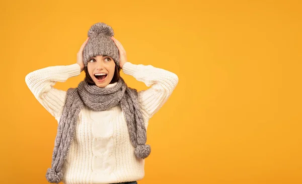 Het is ongelooflijk. Verrast jonge dame in warme trui en gebreide set wordt geschokt om te zien verkoop, gele achtergrond — Stockfoto