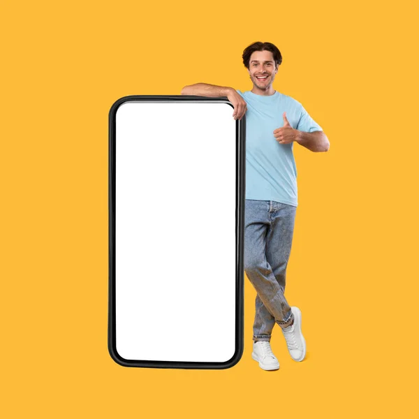 Mutlu adam beyaz boş akıllı telefon ekranı ve başparmak yukarı gösteriyor — Stok fotoğraf