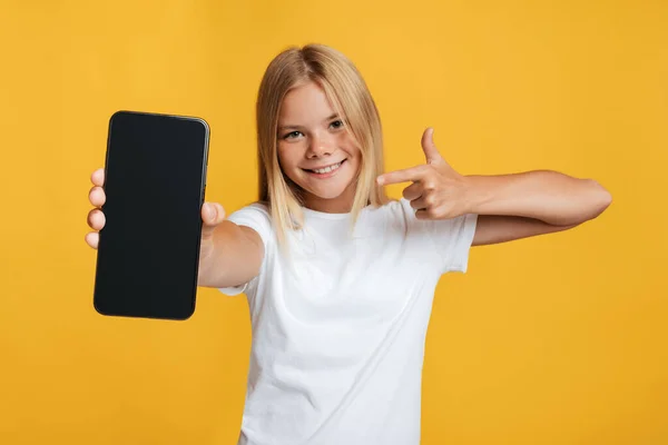 Šťastný roztomilý evropský dospívající blondýnka dívka ukazuje prst na smartphone s prázdnou obrazovkou — Stock fotografie