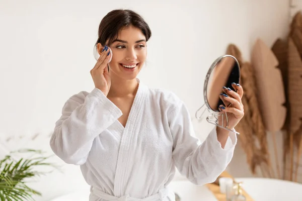 Femmina cura per la pelle utilizzando cotone pad tenendo specchio interno — Foto Stock