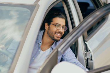 Başarılı bir Orta Doğulu genç adam arabadan çıkıyor.