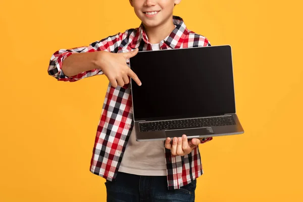 Gülümseyen çekici genç öğrenci boş ekranla dizüstü bilgisayara parmağını gösteriyor. — Stok fotoğraf