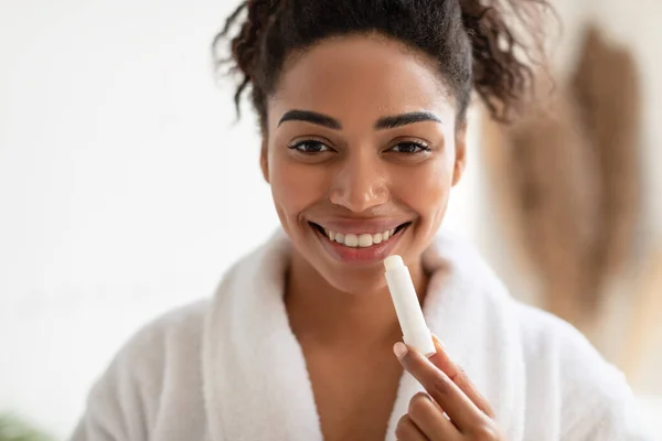 Retrato de mulher negra aplicando bálsamo de lábio no banheiro — Fotografia de Stock