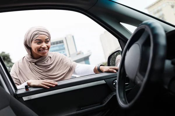 Sonriendo bastante musulmán africano americano mujer comprador en hijab mira en salón de coche nuevo, cliente elegir transporte — Foto de Stock