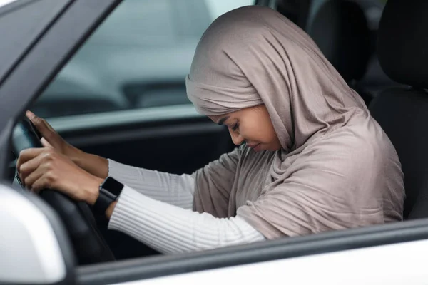 Verontrustende Afro-Amerikaanse dame in hijab rijdende auto, gebogen hoofd en spijt over ongeval, lijdt aan pijn na incident — Stockfoto