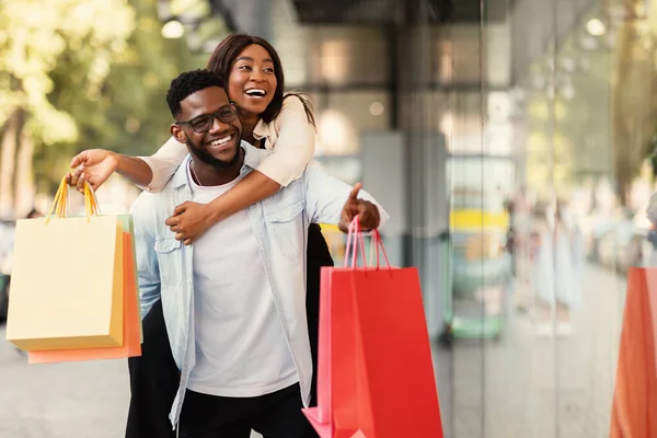 Portrait of black couple with shopping bags pointing at window — Stock Photo, Image